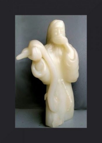 Die weisse Specksteinfigur zeigt eine bärtige Figur, die eine Schöpferfigur (Gott) darstellen soll. Sie hält eine grosse Schlange in der Hand, die den Erdball komplett verschluckt hat und hält sich erschrocken eine Hand vor den Mund.