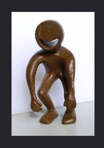 Das Bild zeigt eine braune Specksteinfigur: eine lachende Figur mit schlapp herunterhängenden Armen.