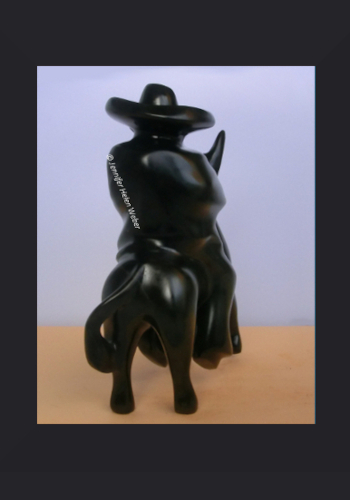 Das Bild zeigt eine schwarze Specksteinfigur: ein Gaucho auf einem Esel von hinten betrachtet