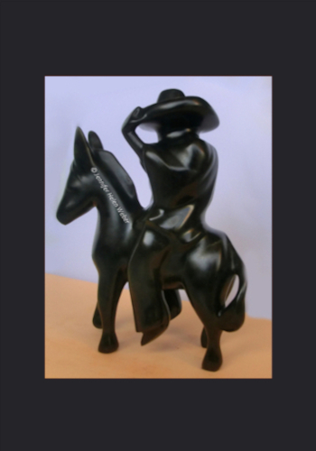 Das Bild zeigt eine schwarze Specksteinfigur ein Gaucho auf einem Esel von der Seite betrachtet.