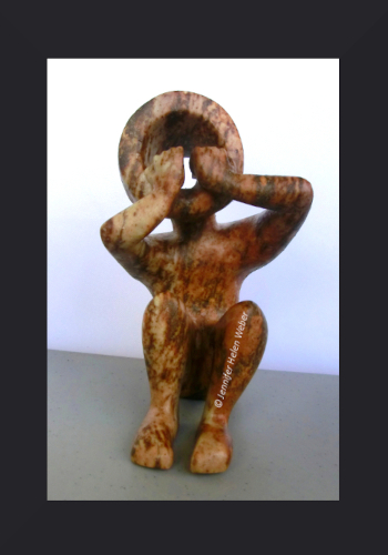Die Specksteinfigur zeigt einen sitzenden Junge, der die Hände ängstlich und entsetzt vor den Mund hält.