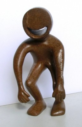 Das Bild zeigt eine braune Specksteinfigur: eine lachende Figur mit schlapp herunterhängenden Armen.