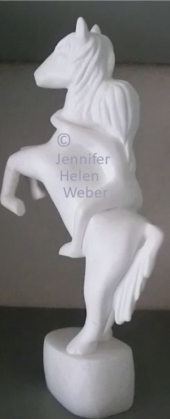 Das Bild zeigt eine weisse Specksteinfigur: eine junge Amazone auf einem steigenden Pferd