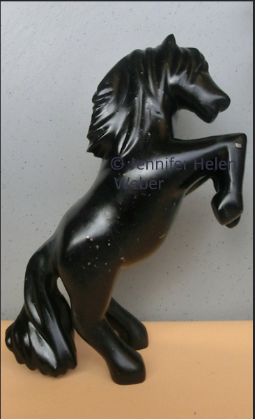 Das Bild zeigt eine Specksteinskulptur: einen steigenen schwarzen Hengst