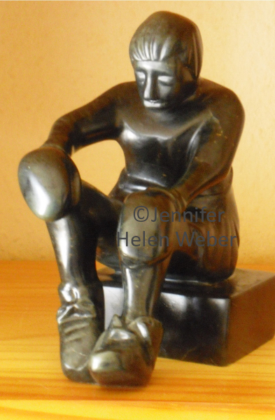 Das Bilder-Rätsel zeigt eine schwarze Specksteinfigur: ein sitzender Boxer mit offenem Schnürsenkel.