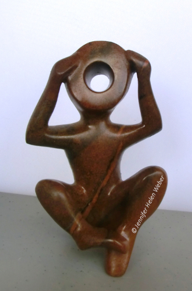 Die Specksteinfigur zeigt einen Kriegswaisen: ein sitzender Junge, der sich die Ohren zuhält.